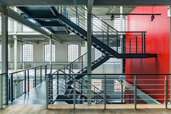 Industrial building interior with red wall and black, metal staircase
